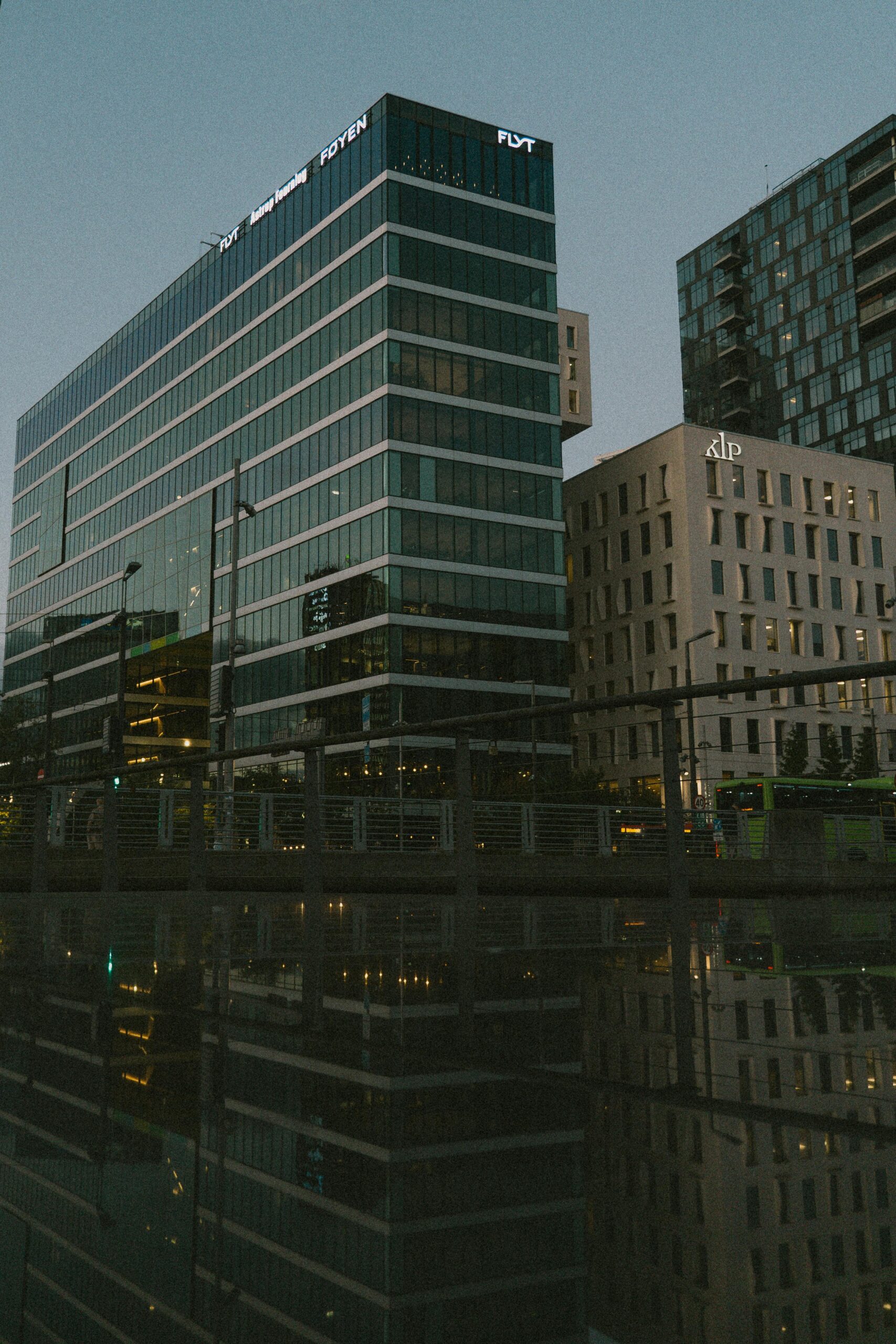 Urban cityscape with modern office buildings reflected at dusk, creating dramatic architecture scene.